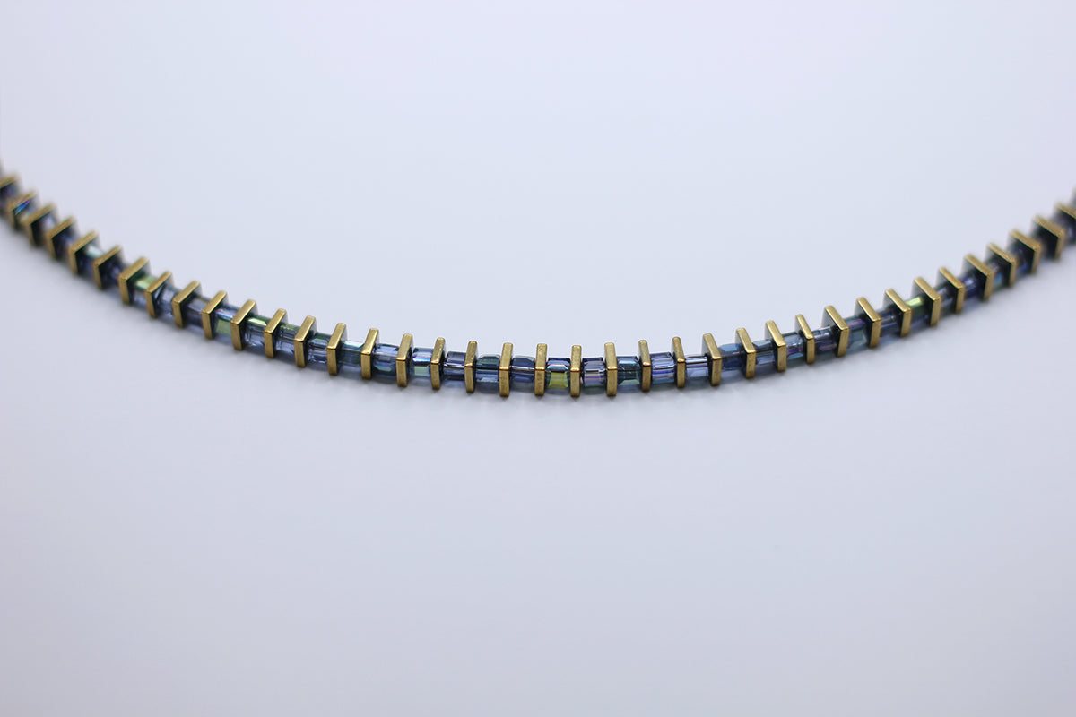 Necklace with blue and gold beads on a light gray background