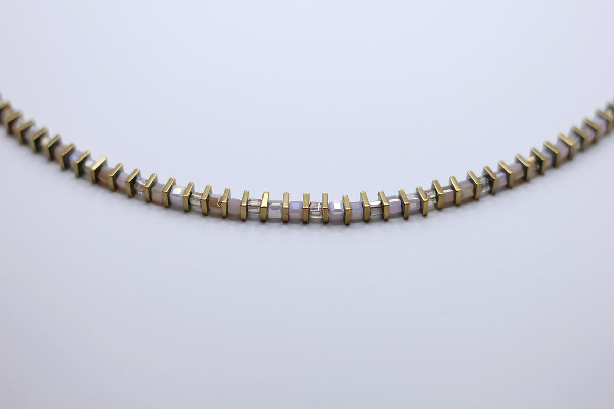 Necklace with gold and white beads on a light gray background
