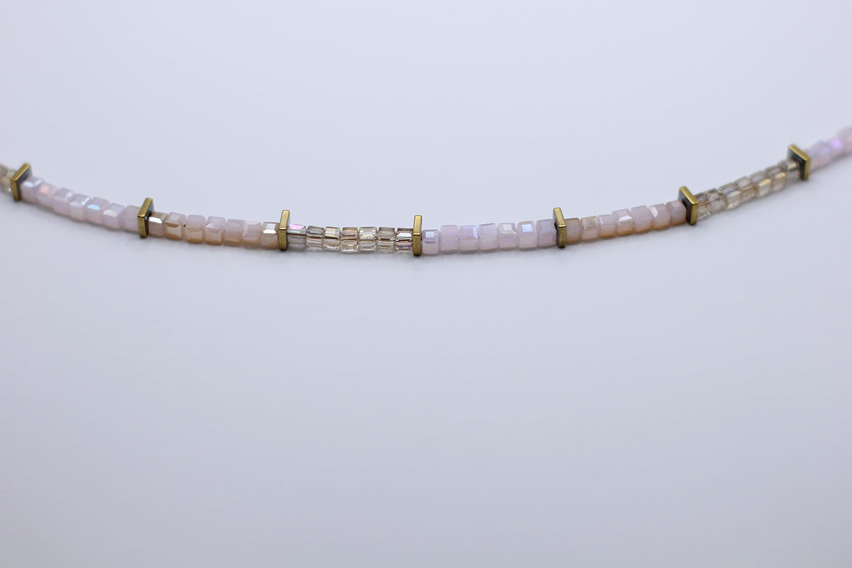 Necklace with pink beads and gold accents on a light gray background