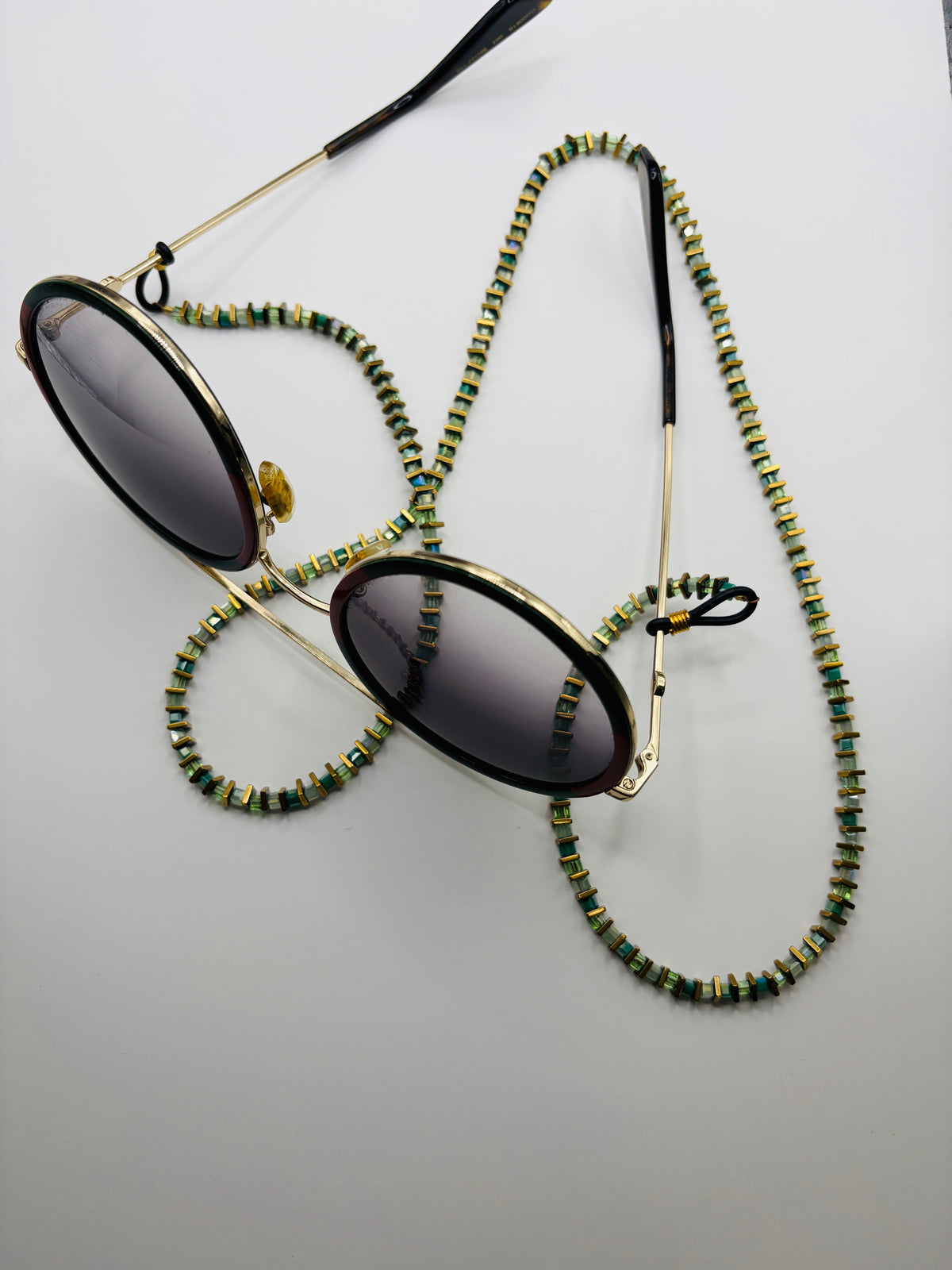 Sunglasses with a beaded chain on a light gray background