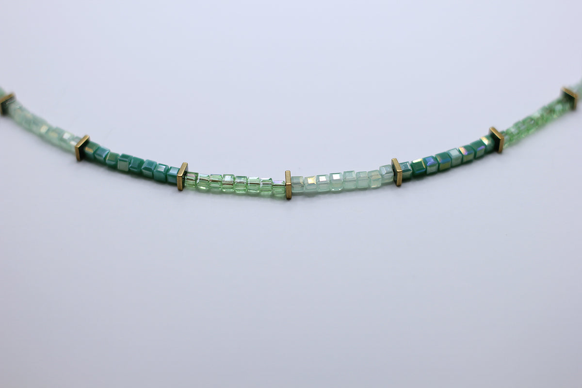 Green beaded necklace on a light gray background